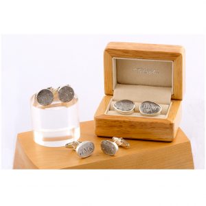 Cufflinks placed on a wooden box. The object is set on a white background.