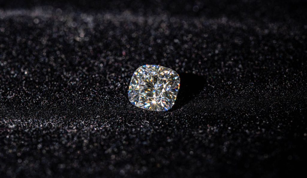 Sparkling clear diamond resting on a black surface